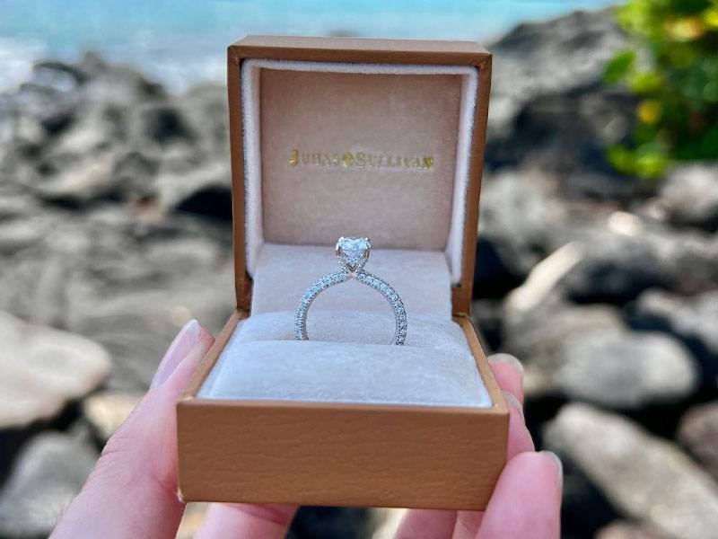The Juhas and Sullivan jewelry collection features a wide variety of dimoand engagement rings, as shown in a signature open box on the seashore.
